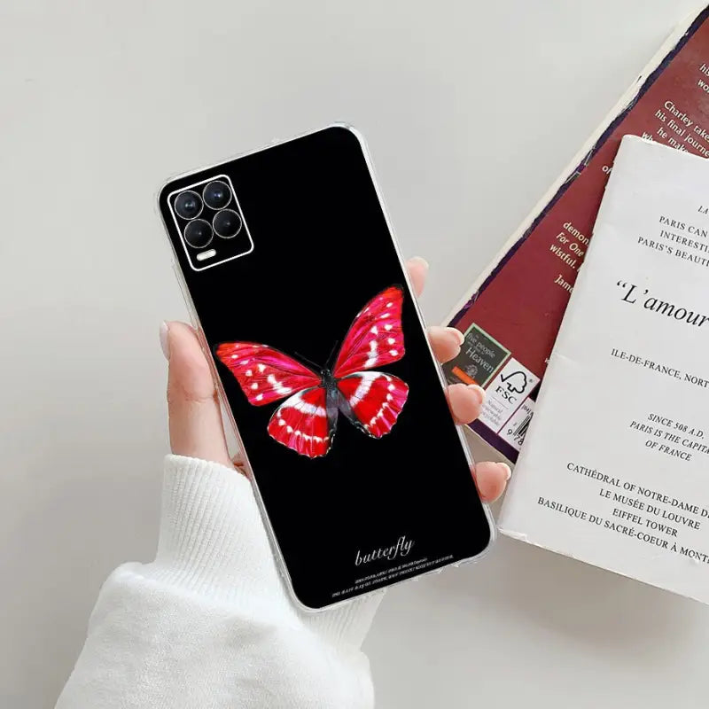 a woman holding a phone case with a red butterfly on it