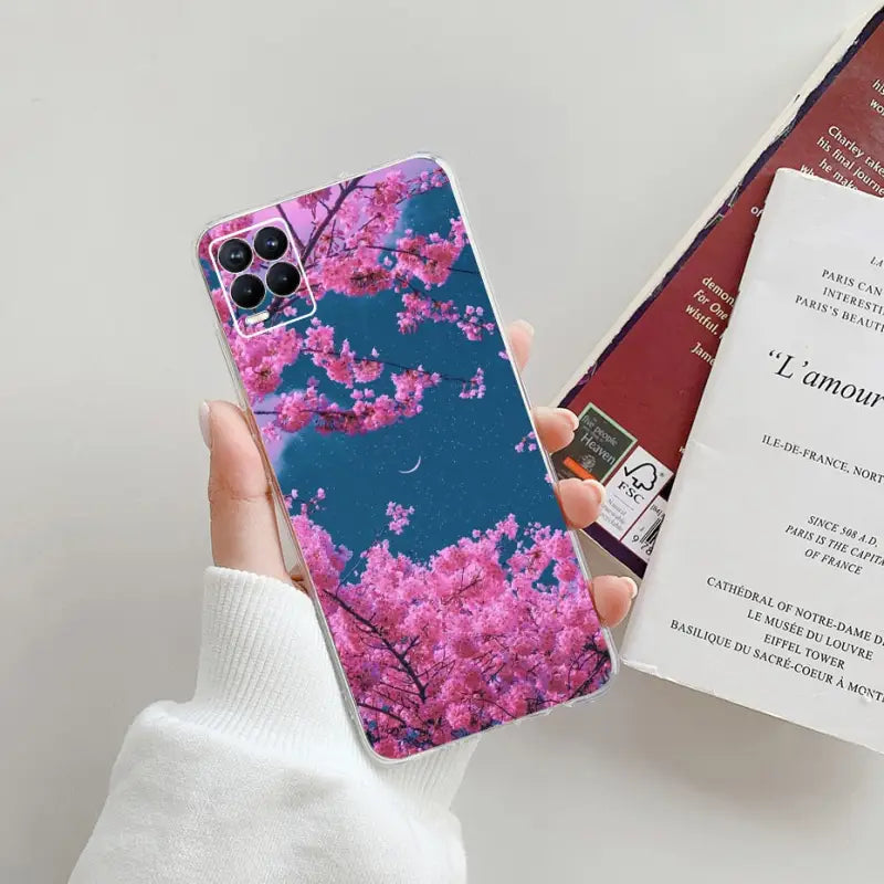 a person holding a phone case with a pink cherry blossom on it