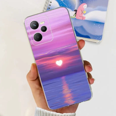 a person holding a phone with a sunset painting on it