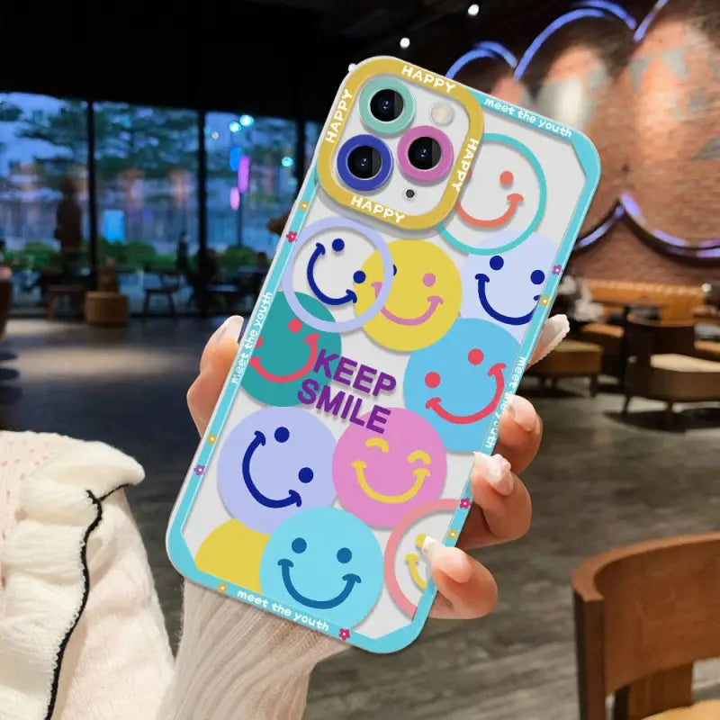 a person holding up a phone case with smiley faces