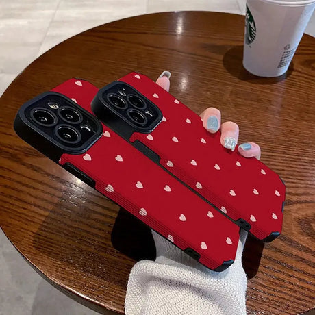 a woman holding a red phone case with white hearts on it