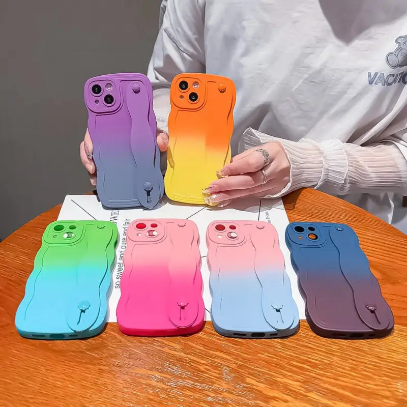 a person holding a phone case with a rainbow colored case