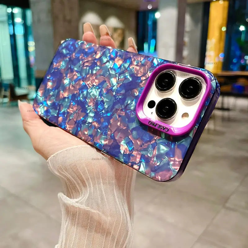 a woman holding up a phone case with a purple and blue marble pattern