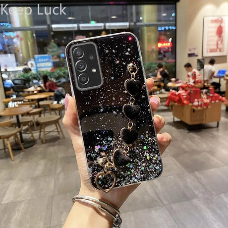 a woman holding up a phone case with a black and white glitter design