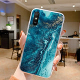 a woman holding up a phone case with a blue marble pattern