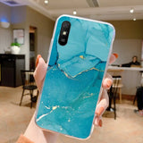 a person holding up a phone with a blue marble case