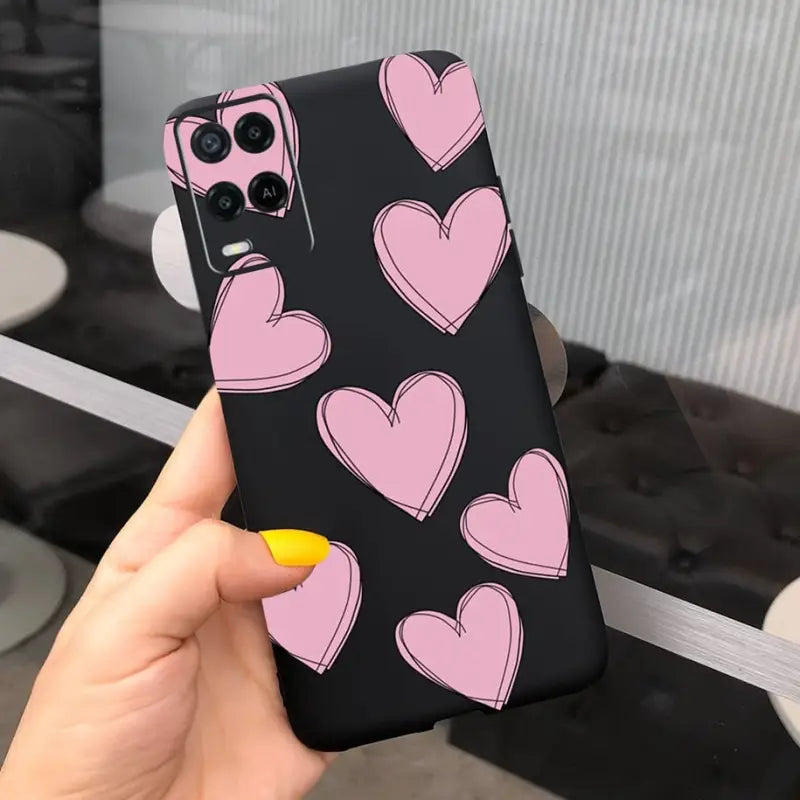 a woman holding up a phone case with pink hearts on it
