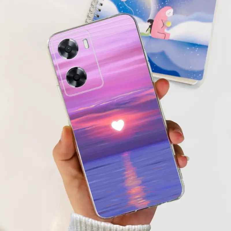 a person holding a phone case with a sunset in the background