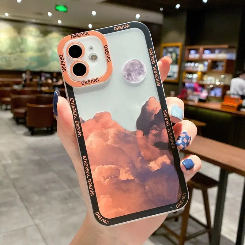 a woman holding a phone case with a picture of a sky and clouds