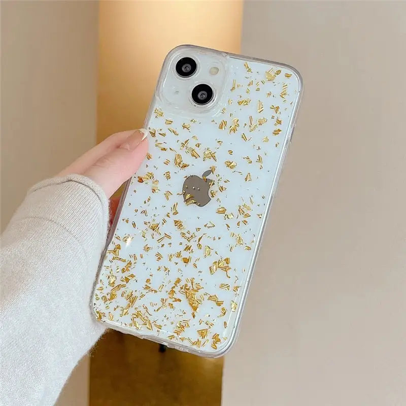 a woman holding a white and gold iphone case