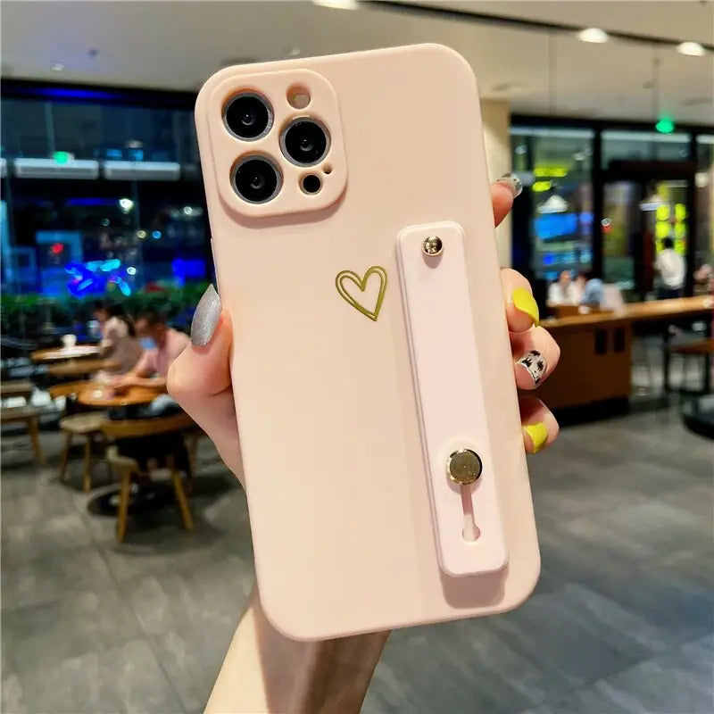 a woman holding a pink iphone case with a heart on it