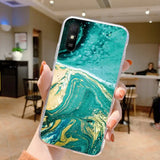 a person holding a phone with a green and gold marble pattern