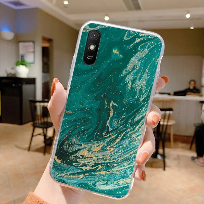 a person holding up a green marble phone case