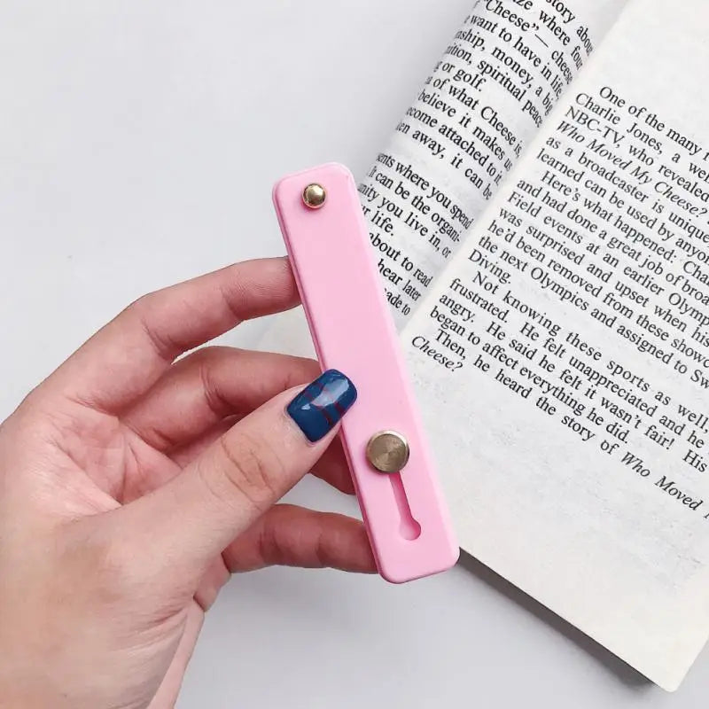 a hand holding a pink bookmark with a bookmark in the background