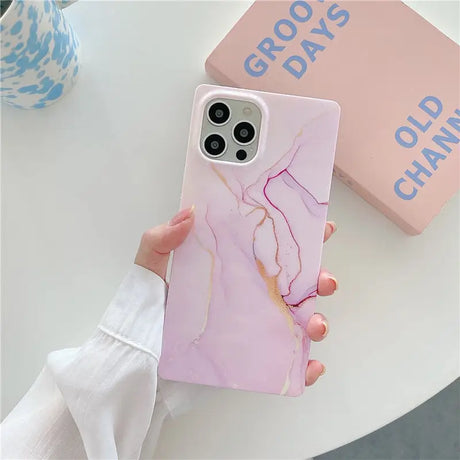 a person holding a pink marble phone case