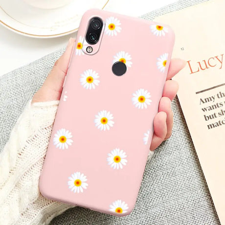 a person holding a pink phone case with daisies on it