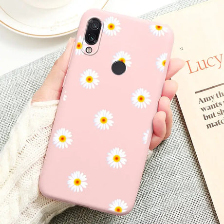 a person holding a pink phone case with daisies on it