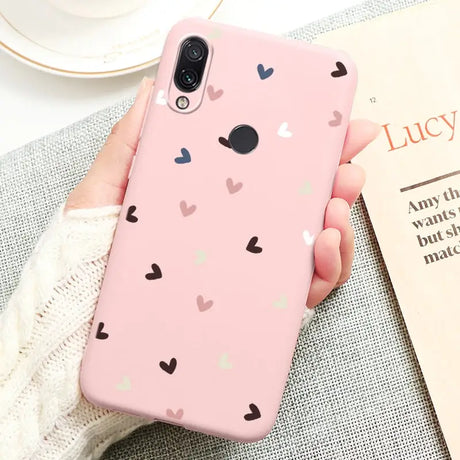 a woman holding a pink phone case with hearts on it