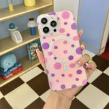a person holding a pink and purple polka dot phone case
