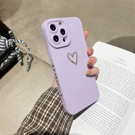 a woman holding a purple phone case with a heart on it