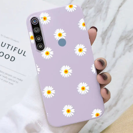 a close up of a person holding a purple phone case with daisies on it