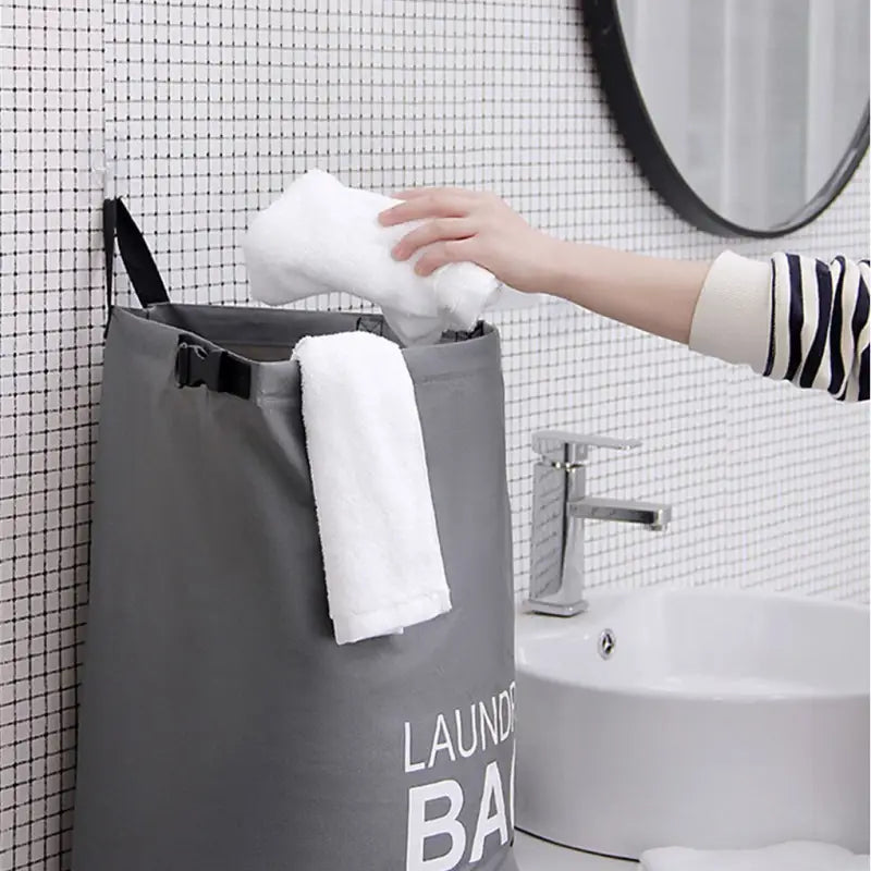a person holding a towel over a gray laundry bag