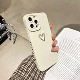 a woman holding a white phone case with a heart drawn on it