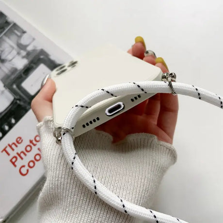 a person holding a white phone with a white cable