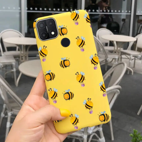 a person holding up a yellow phone case with bees on it