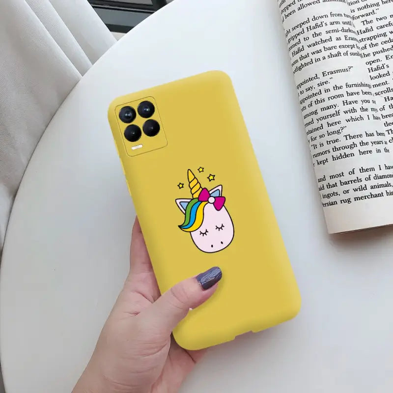 a person holding a yellow phone case with a unicorn on it