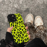 a person holding a yellow phone case with black and white leopard print