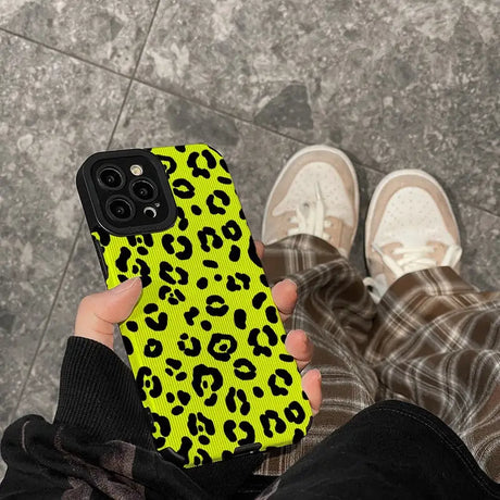 a person holding a yellow phone case with black and white leopard print