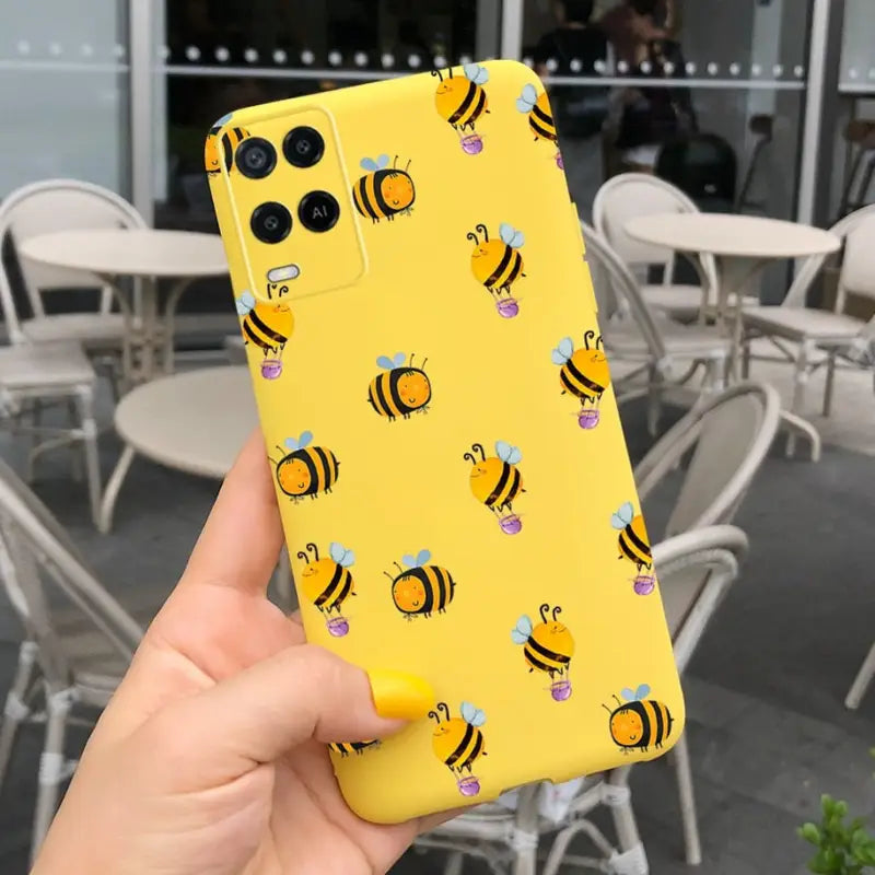 a person holding up a yellow phone case with bees on it