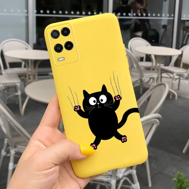 a person holding up a yellow phone case with a black cat on it