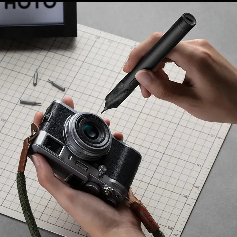 a person holding a pen and taking a photo of a camera