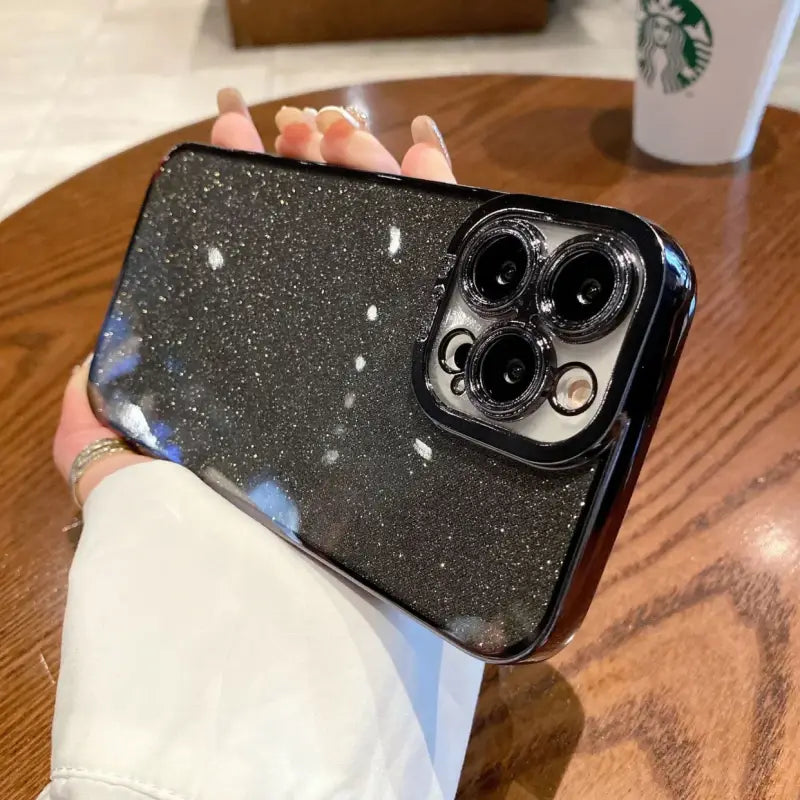 a person holding a phone with a black glitter case