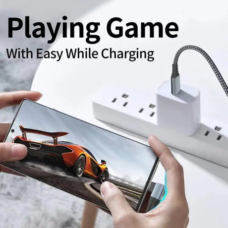 A person holding a phone with a charging cable