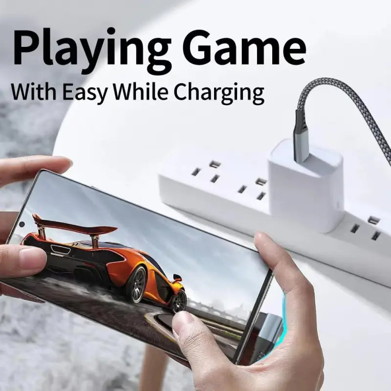 A person holding a phone with a charging cable
