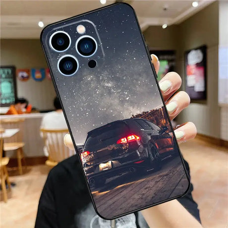 A person holding up a phone case with a car in the background