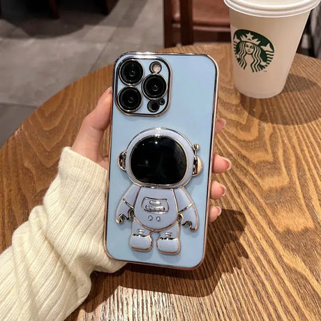 A person holding a phone case with a coffee cup in the background