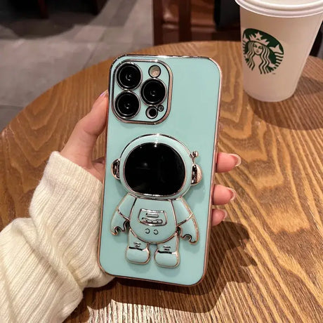 A person holding a phone case with a coffee cup in the background