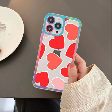 A person holding a phone case with hearts on it