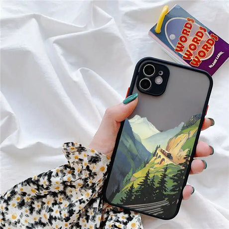 A person holding a phone case with a mountain scene on it