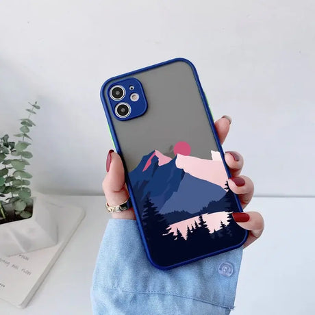 A person holding a phone case with a mountain scene