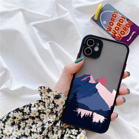 A person holding a phone case with a mountain scene