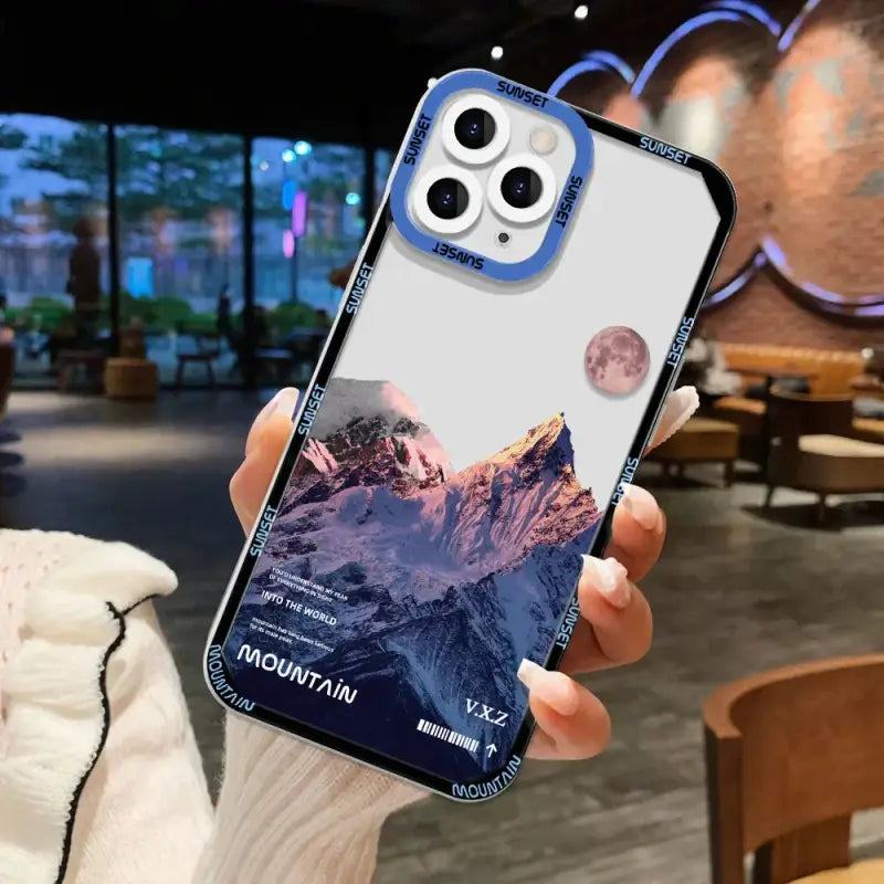 a person holding a phone case with a mountain scene