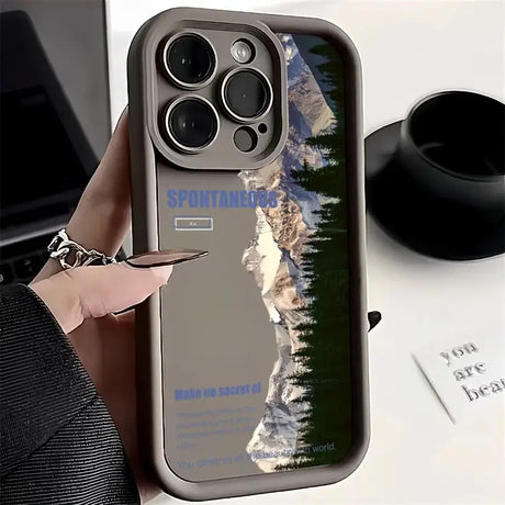 a person holding a phone case with a mountain scene