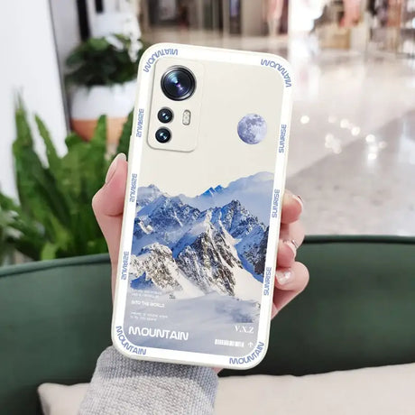 A person holding up a phone case with a mountain scene