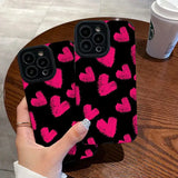 a person holding a phone case with pink hearts on it