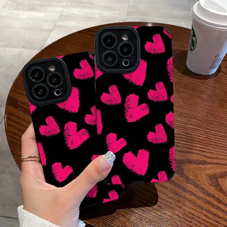 A person holding a phone case with pink hearts on it